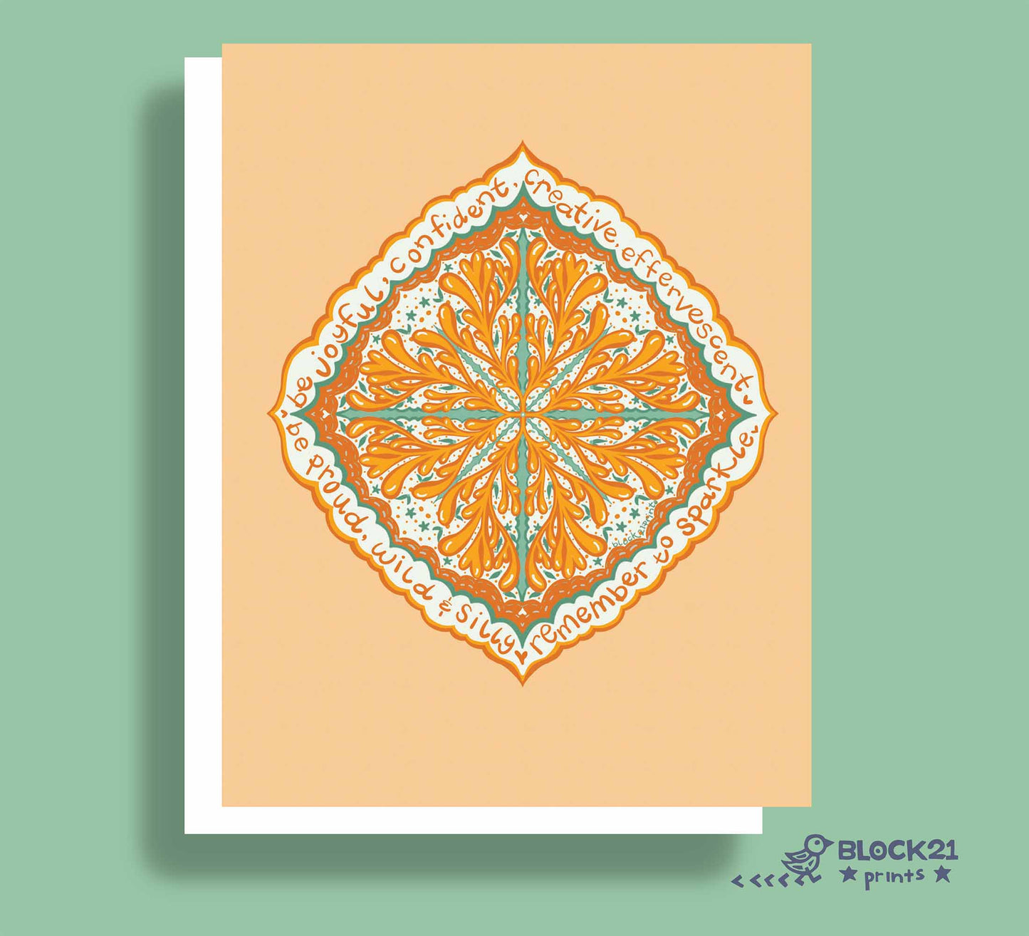 A square art print or greeting card featuring a symmetrical mandala-style floral design in orange, teal, and white on a peach background, shown with a white border and drop shadow against a sage green backdrop. The brand name BLOCK21 prints appears in the bottom right corner.
