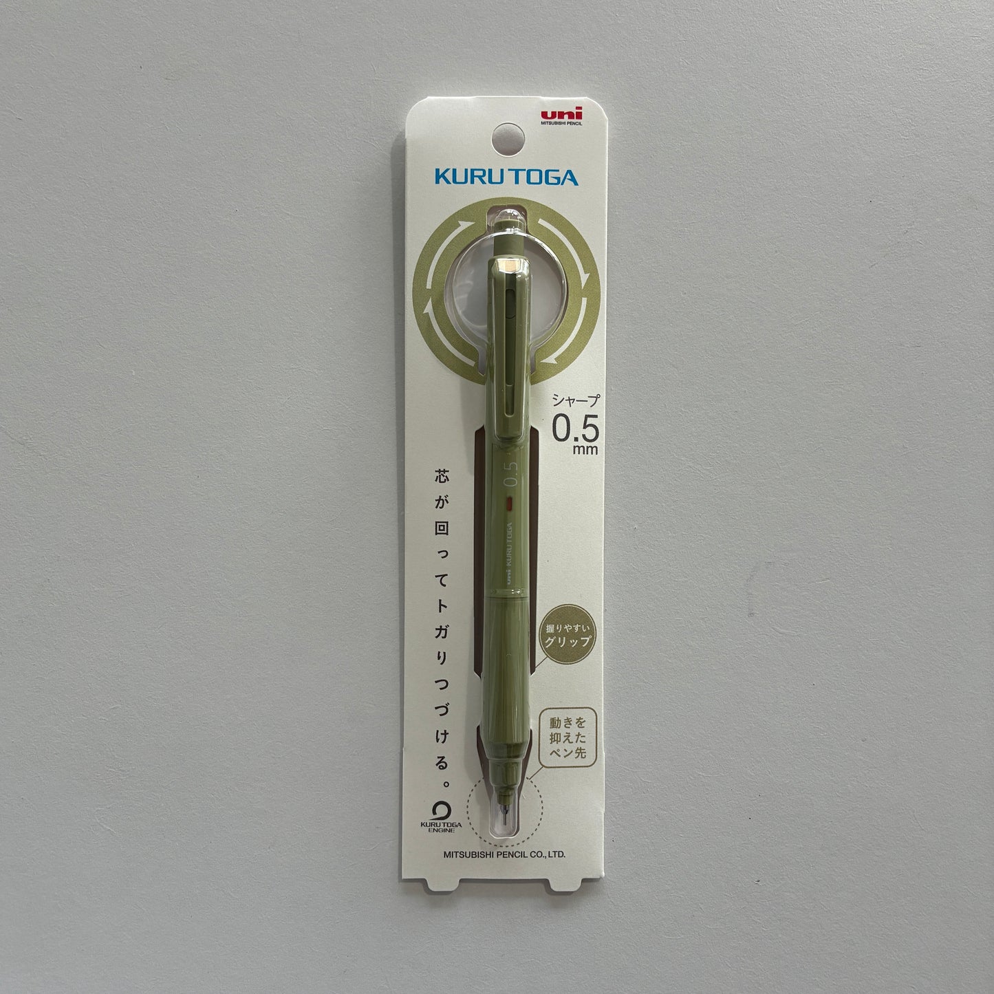 A green Kuru Toga mechanical pencil in its packaging on a gray background