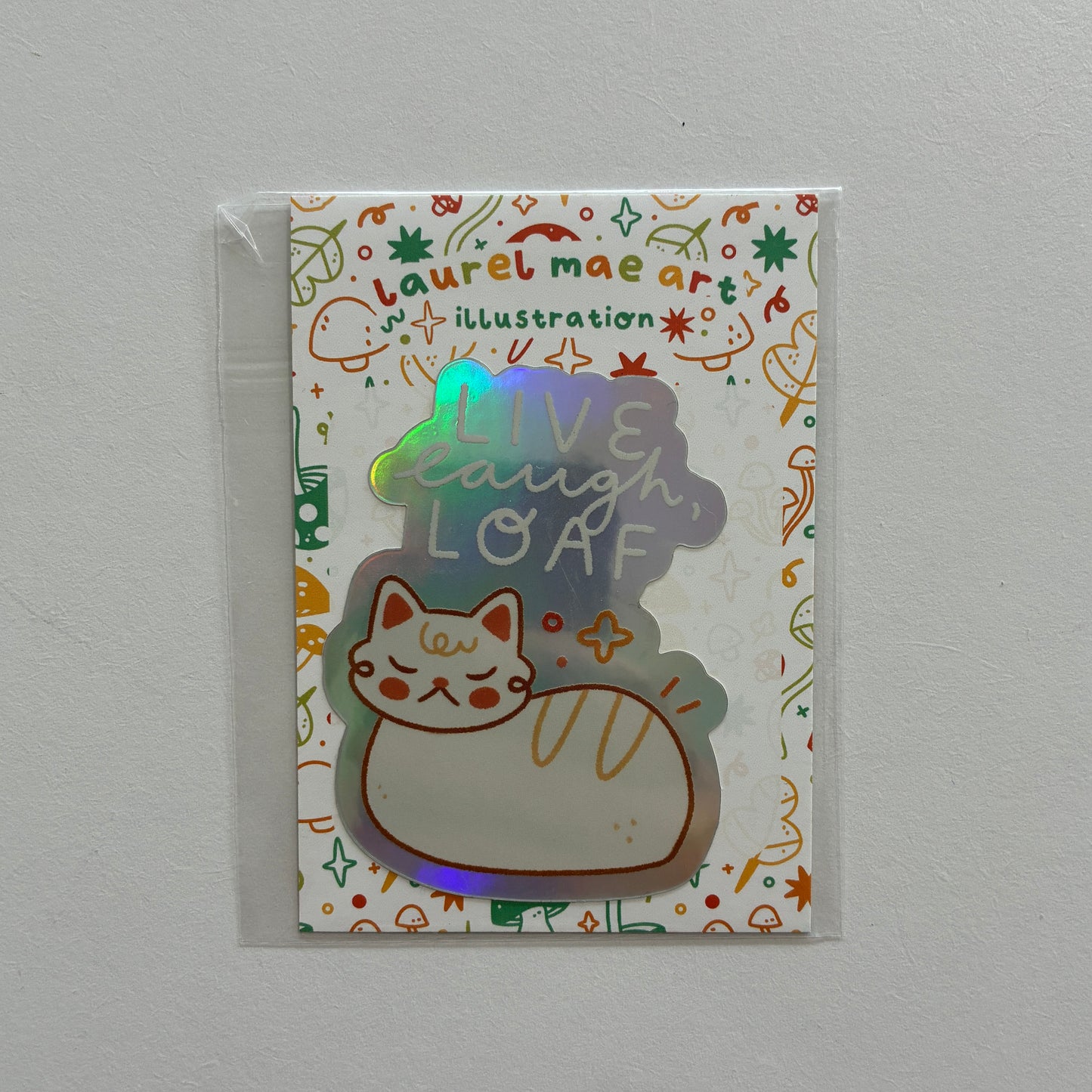 Sticker with cat illustration and text saying “live laugh loaf”