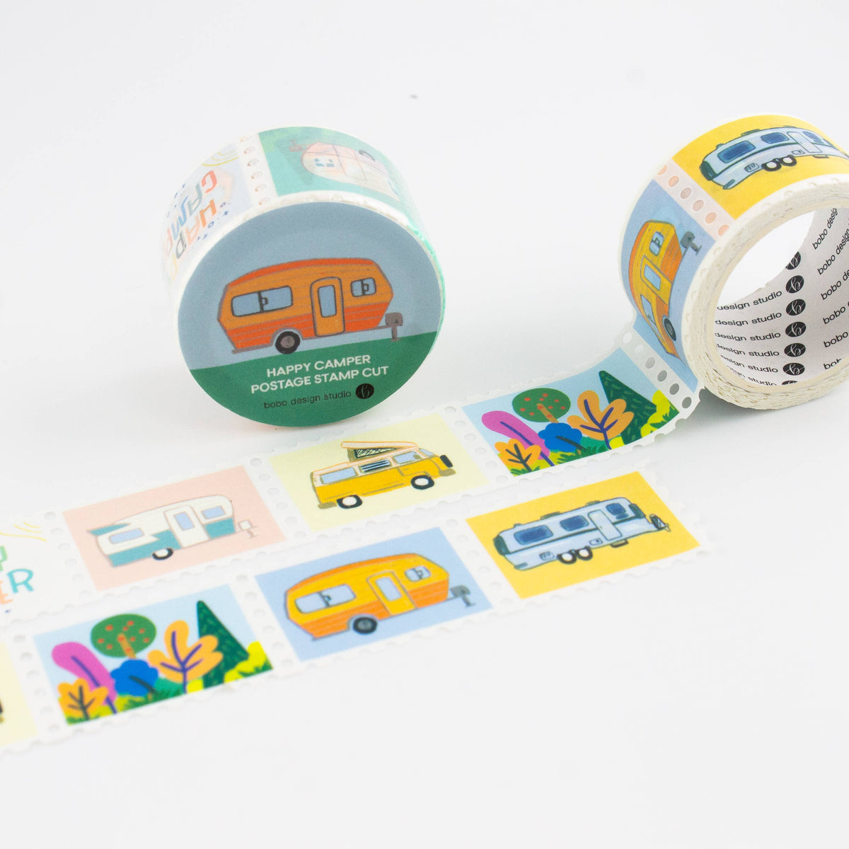 Two rolls of washi tape with a retro camping theme, featuring illustrations of campers, vans, trees, and colorful clouds, with a strip of the tape unrolled on a white background.
