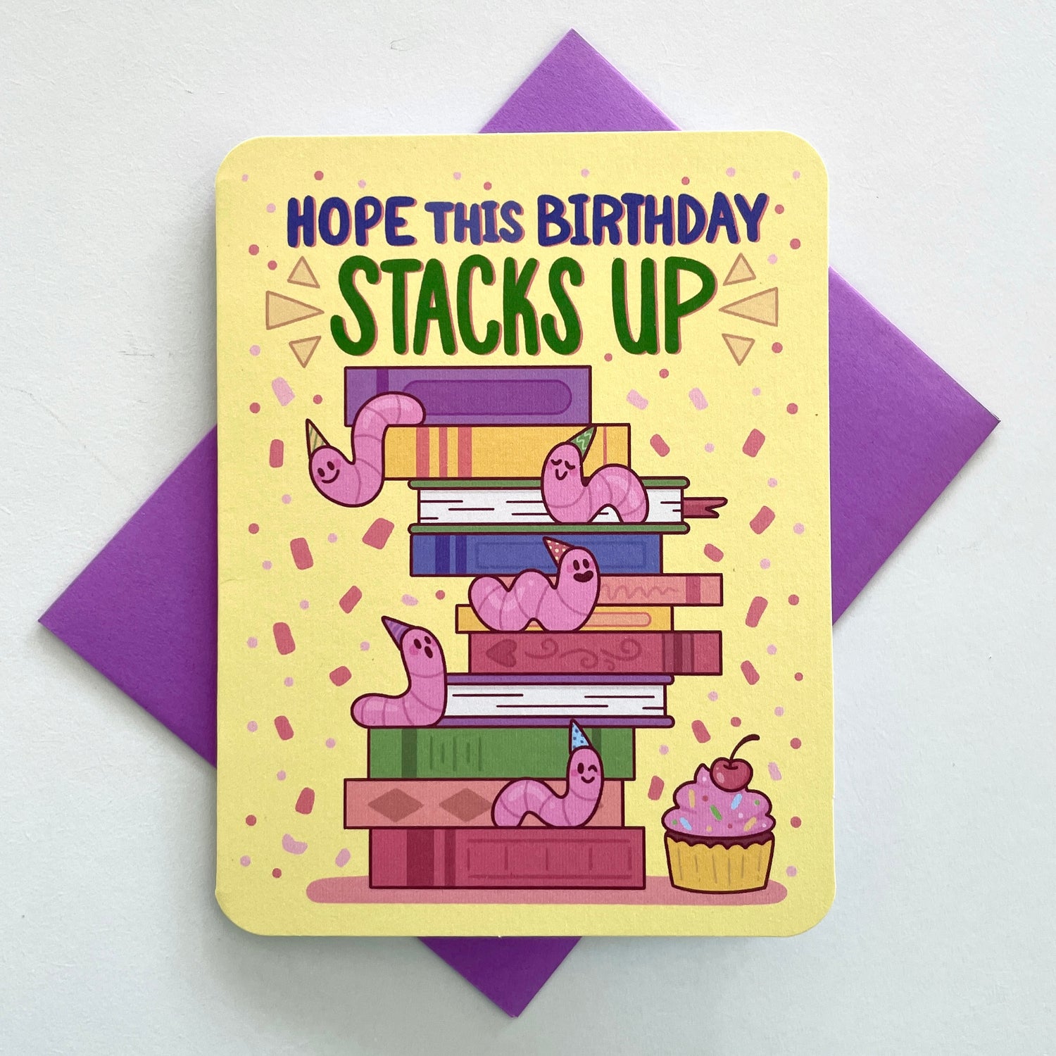 A colorful birthday card with a stack of books and worms, with the phrase 'Hope this birthday stacks up' written on it. 