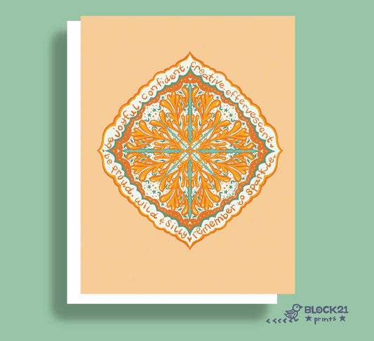 A square art print or greeting card featuring a symmetrical mandala-style floral design in orange, teal, and white on a peach background, shown with a white border and drop shadow against a sage green backdrop. The brand name BLOCK21 prints appears in the bottom right corner.