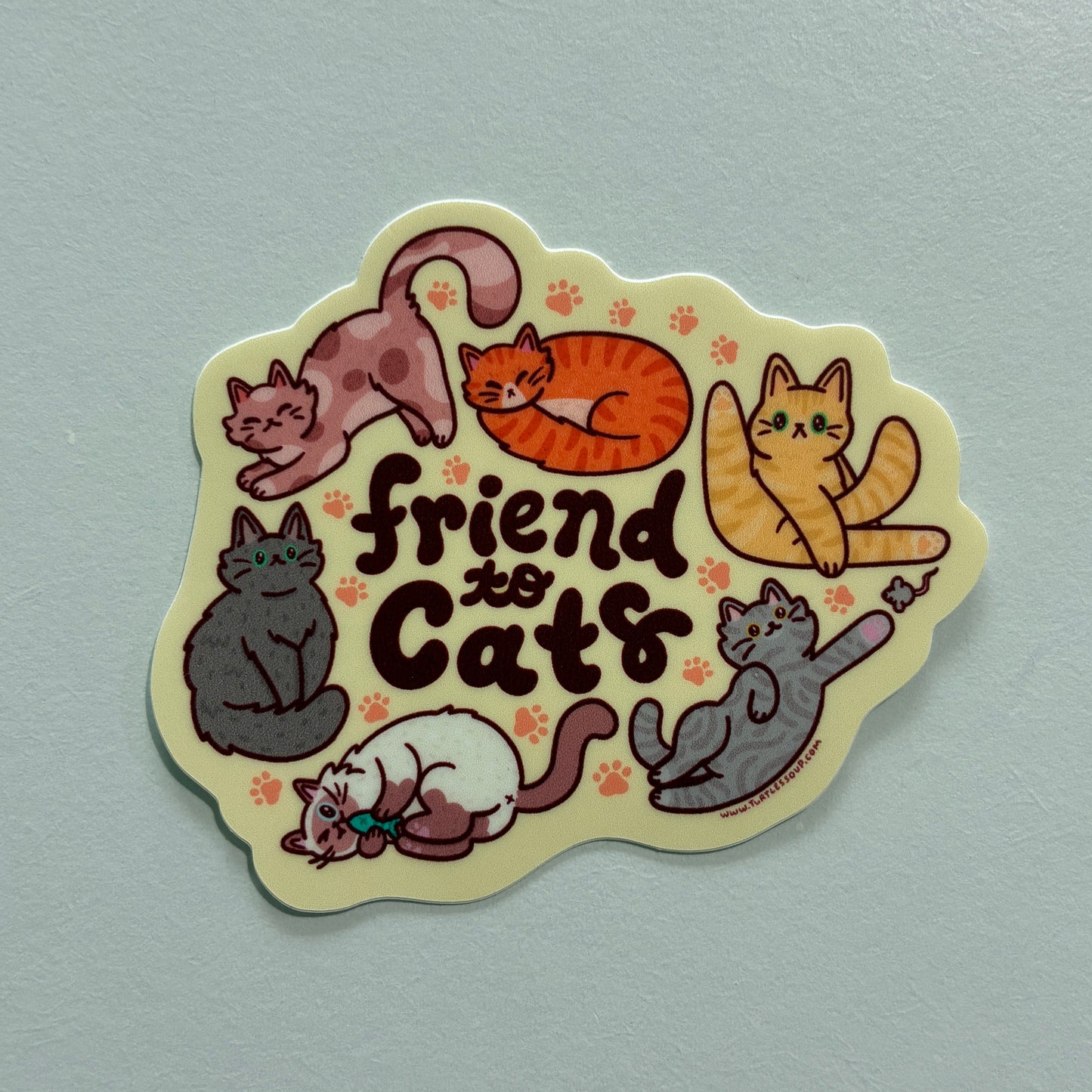 A sticker with several cat illustrations and text saying “friend to cats” on a gray background