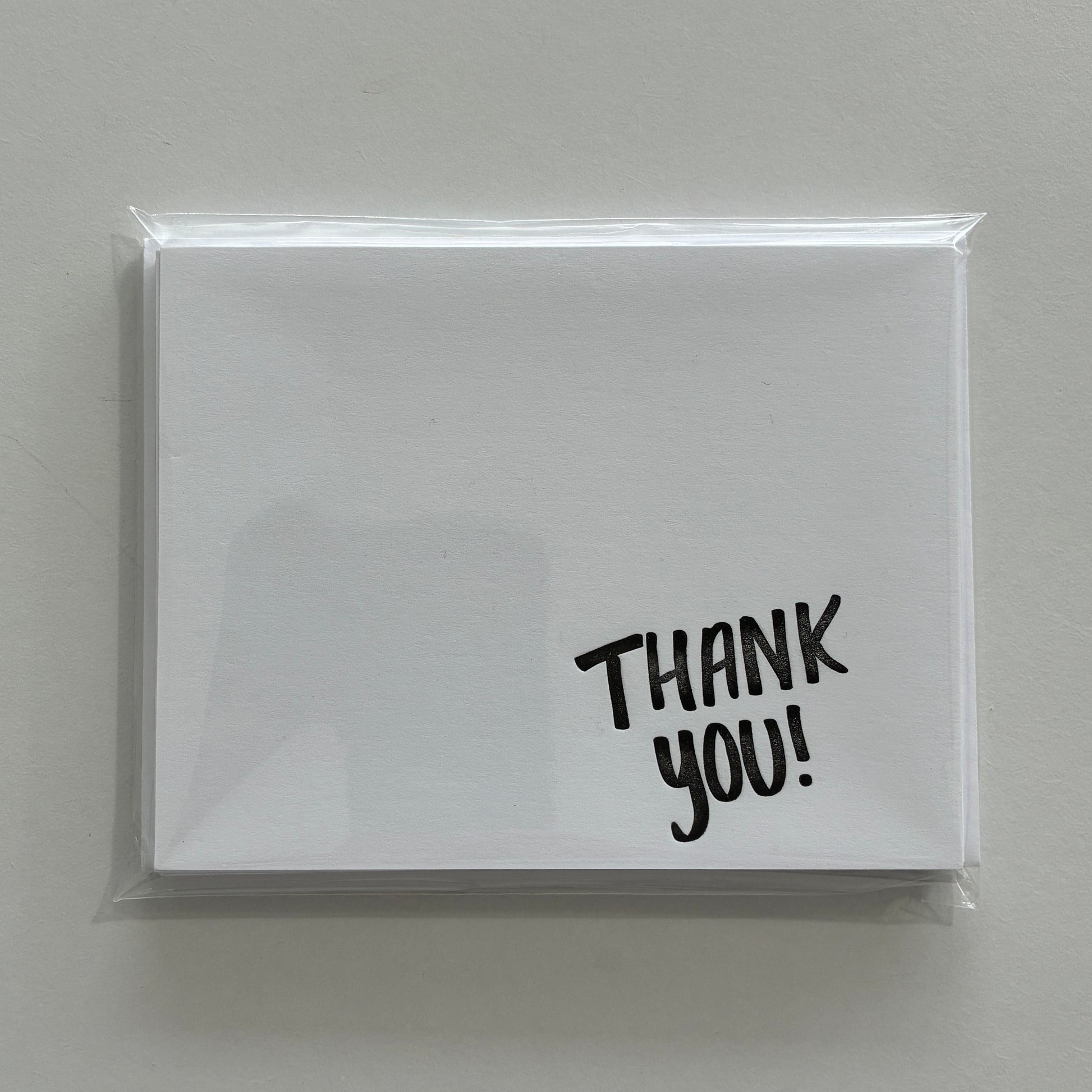 White notecard set with 'THANK YOU!' text on a gray background