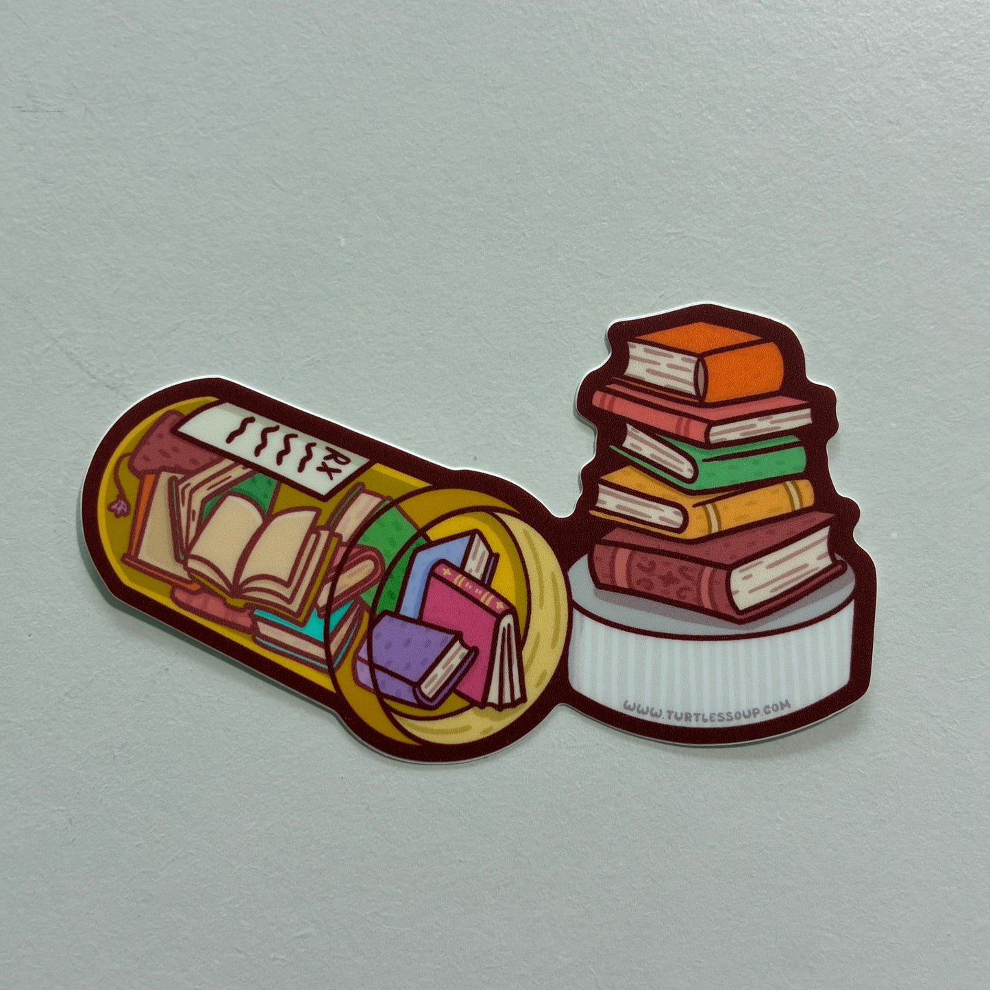 A sticker featuring a drawing of several books inside of a prescription bottle against a gray background