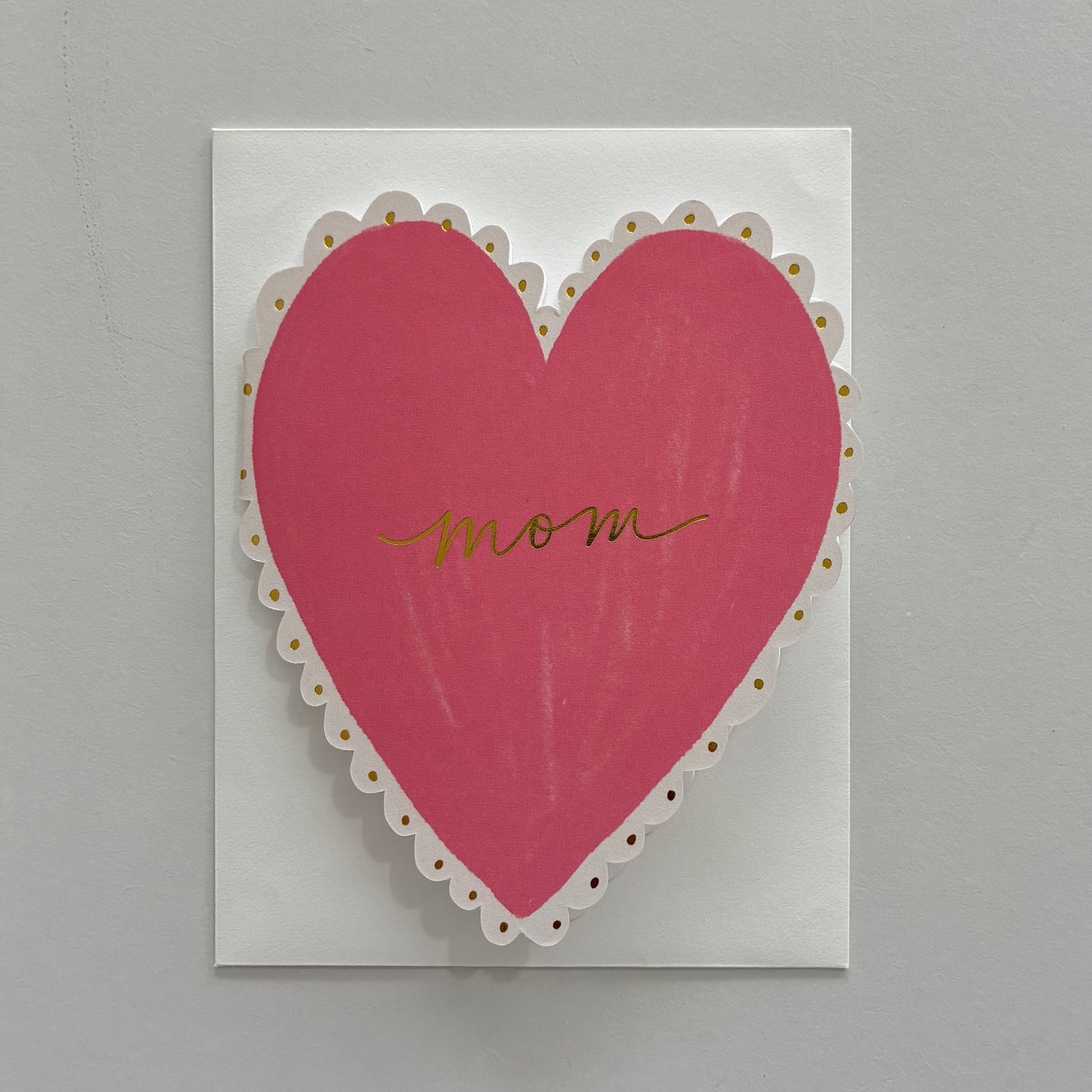 Card with a pink heart and 'mom' written on it against a gray background