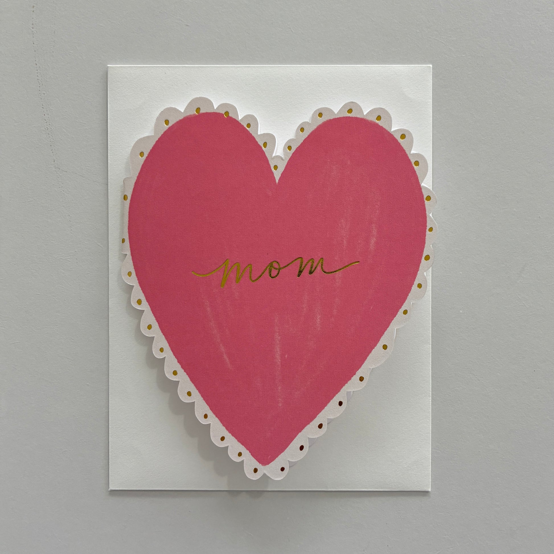 Card with a pink heart and 'mom' written on it against a gray background