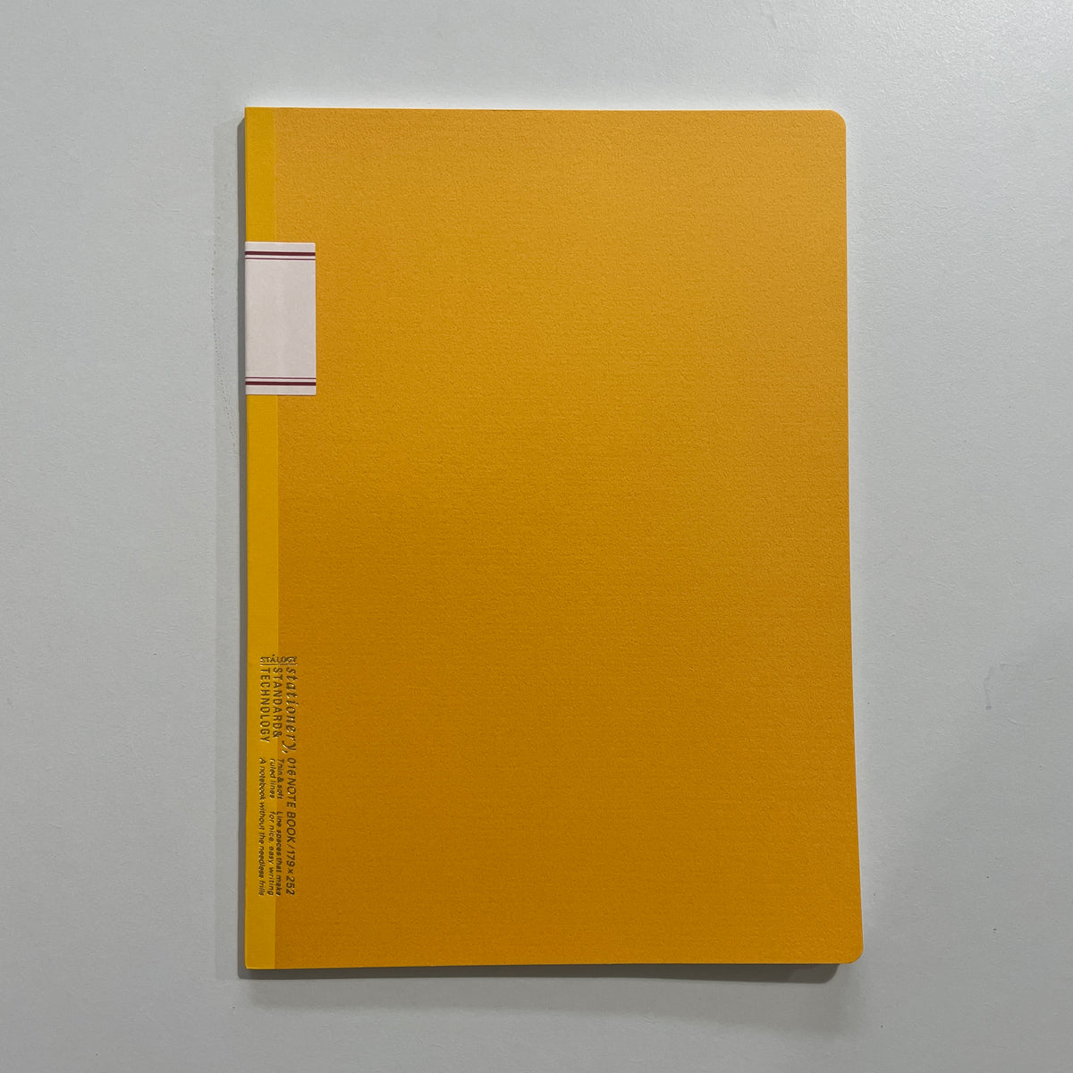 Yellow notebook with a white label on a gray background