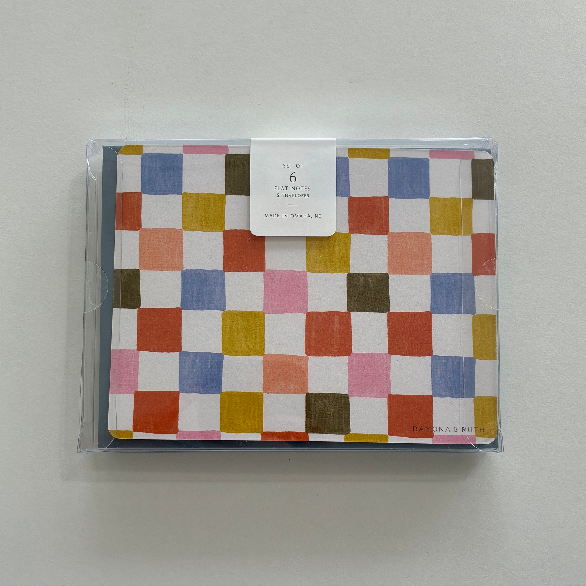 Packaged set of colorful checkered notecards on a light gray background