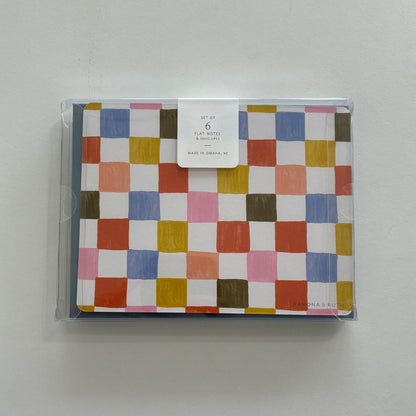 Packaged set of colorful checkered notecards on a light gray background
