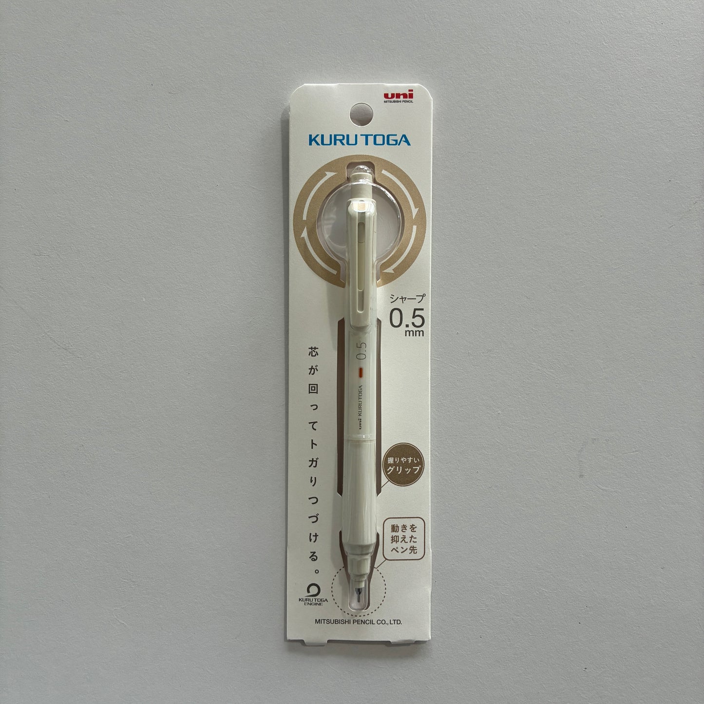 A white Kuru Toga mechanical pencil in its packaging on a gray background