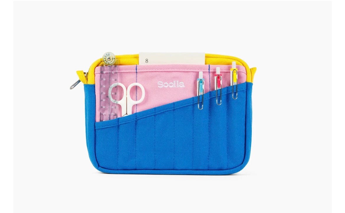 A blue and yellow zippered pouch organizer with multiple pockets, shown open on a light gray background. Inside, a pink organizer insert holds scissors and pens, with the brand name visible.