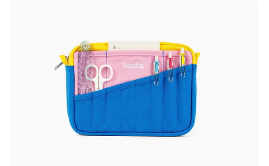 A blue and yellow zippered pouch organizer with multiple pockets, shown open on a light gray background. Inside, a pink organizer insert holds scissors and pens, with the brand name visible.
