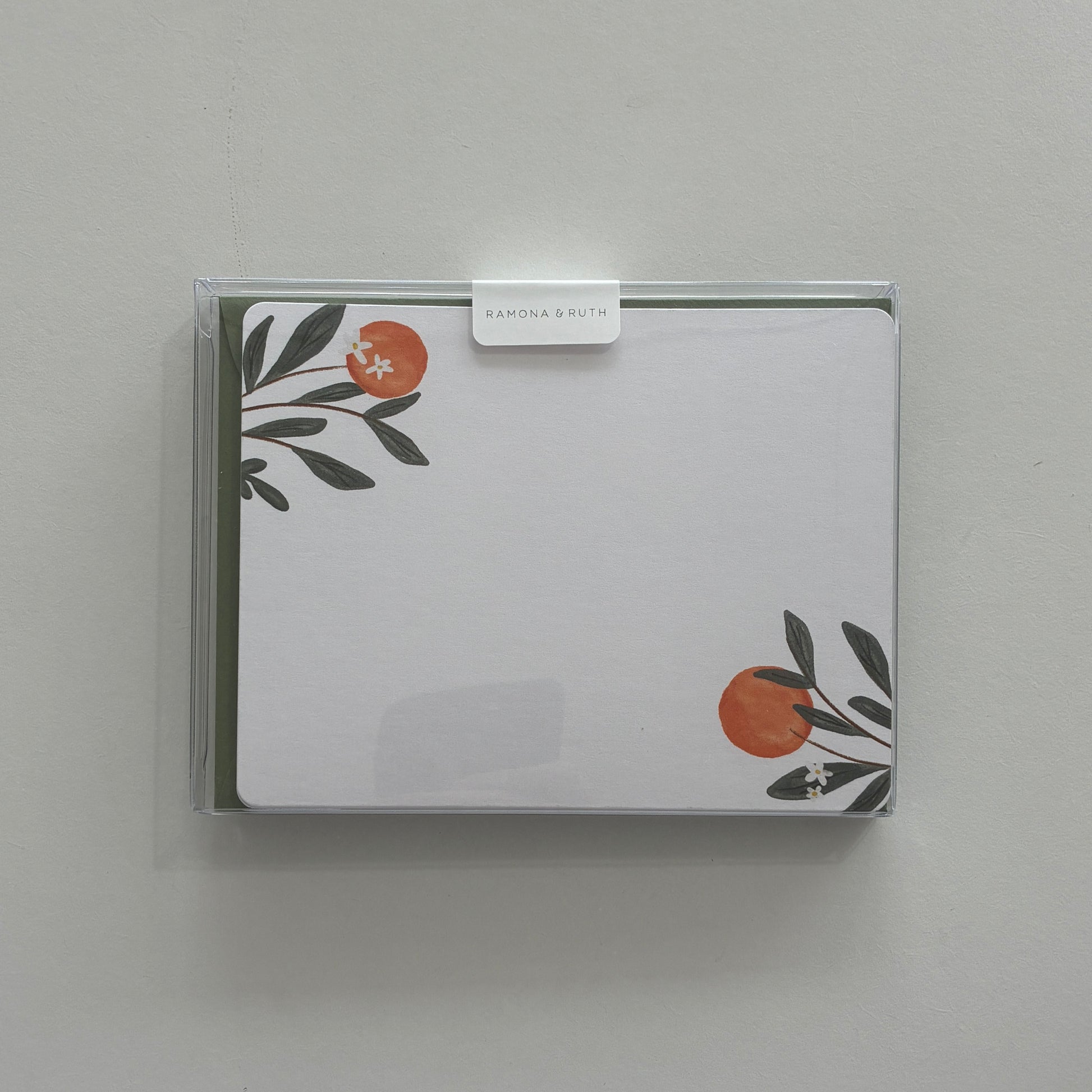 Packaged stationery set with orange floral design on a plain background