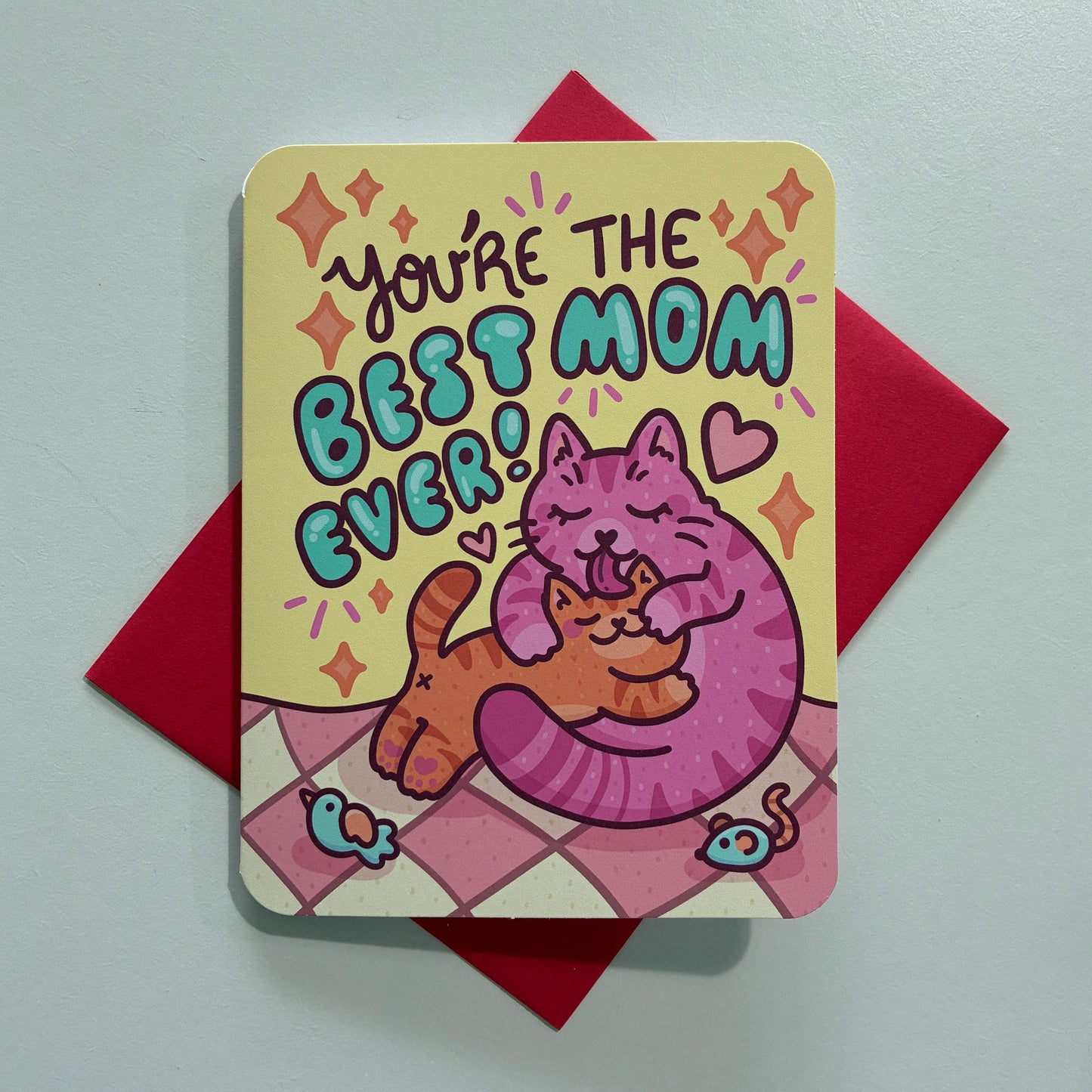 Card with cartoon cat drawing and text saying “you’re the best mom ever” on a gray background
