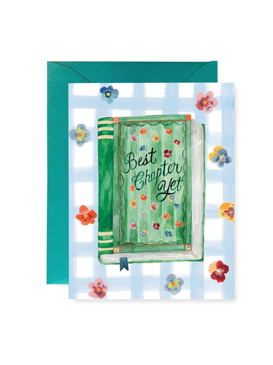 A greeting card with a teal envelope, featuring a watercolor illustration of an open green book with the words 'Best Chapter Yet' on a light blue and white gingham background with small colorful flowers.